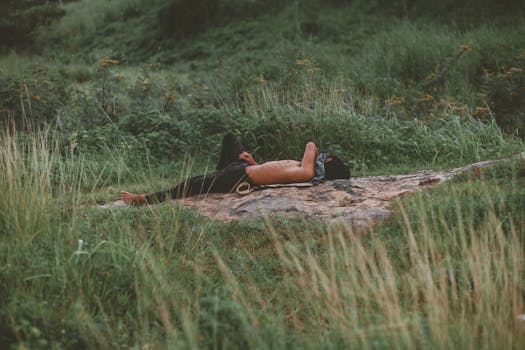 A serene scene of a shirtless man relaxing on a rock in a verdant meadow, capturing tranquility.