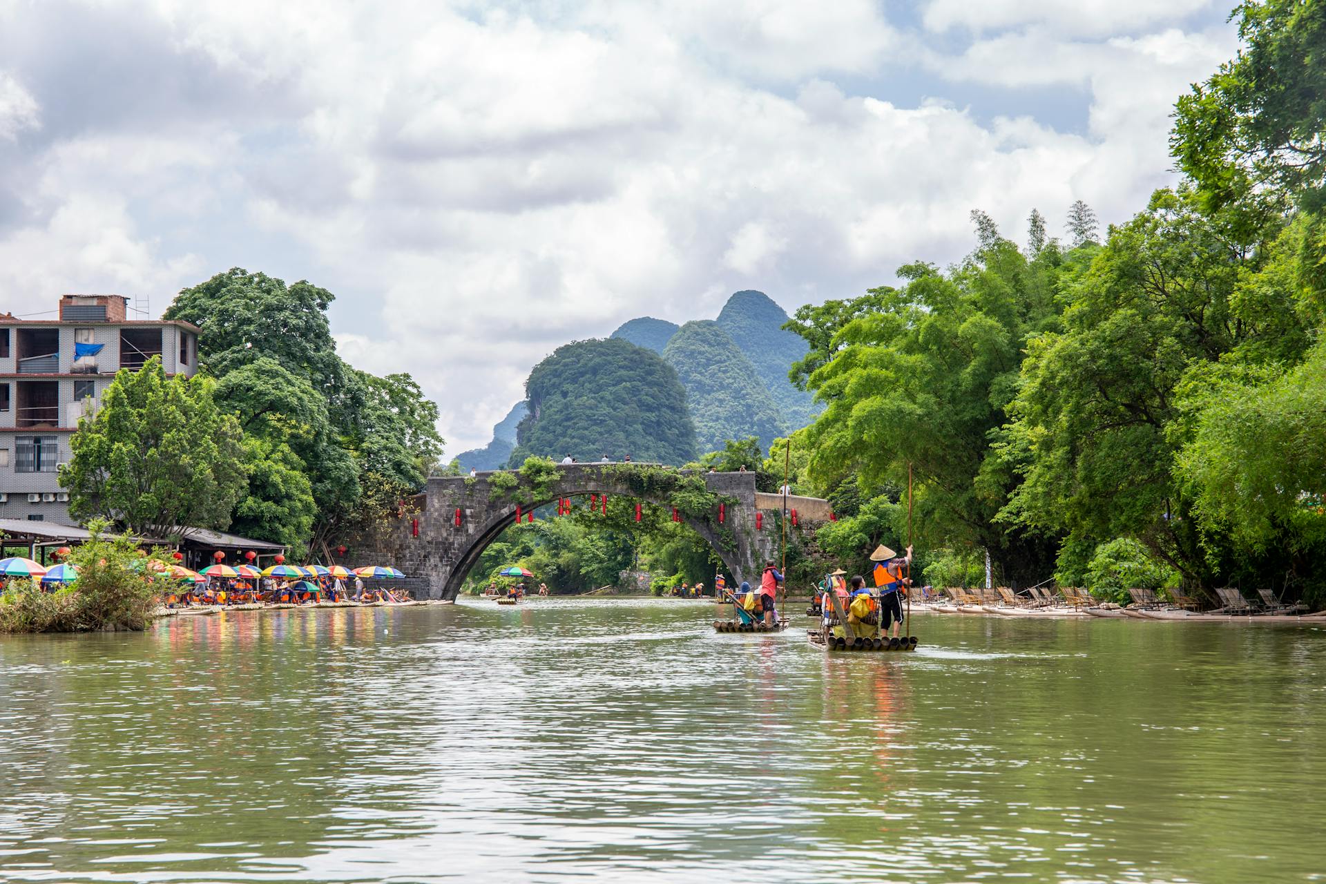 Experience traditional bamboo rafting on a picturesque river in Vietnam, surrounded by lush greenery and mountains.