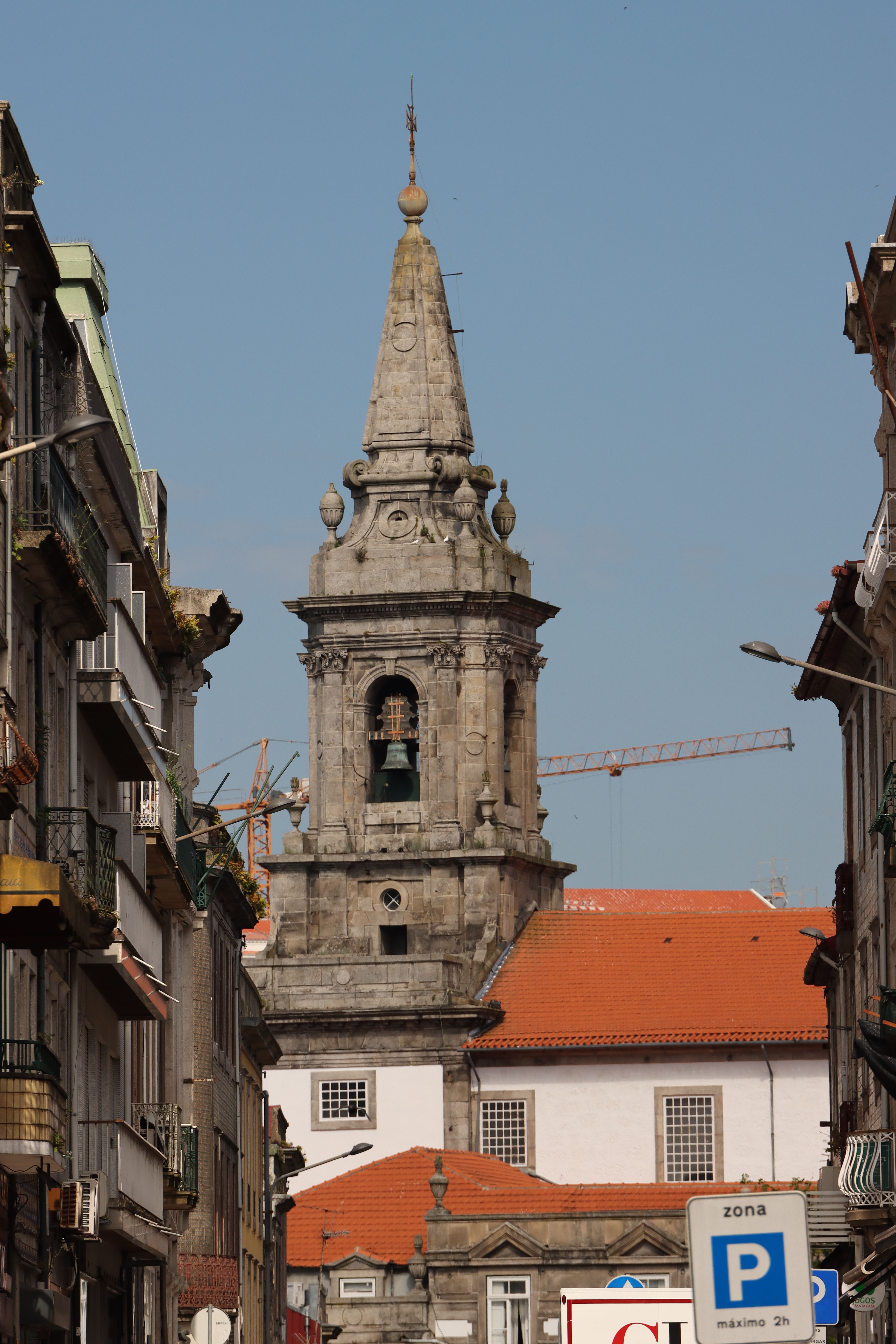 View of the historic bell tower and cityscape in Porto, Portugal, under a clear blue sky.
