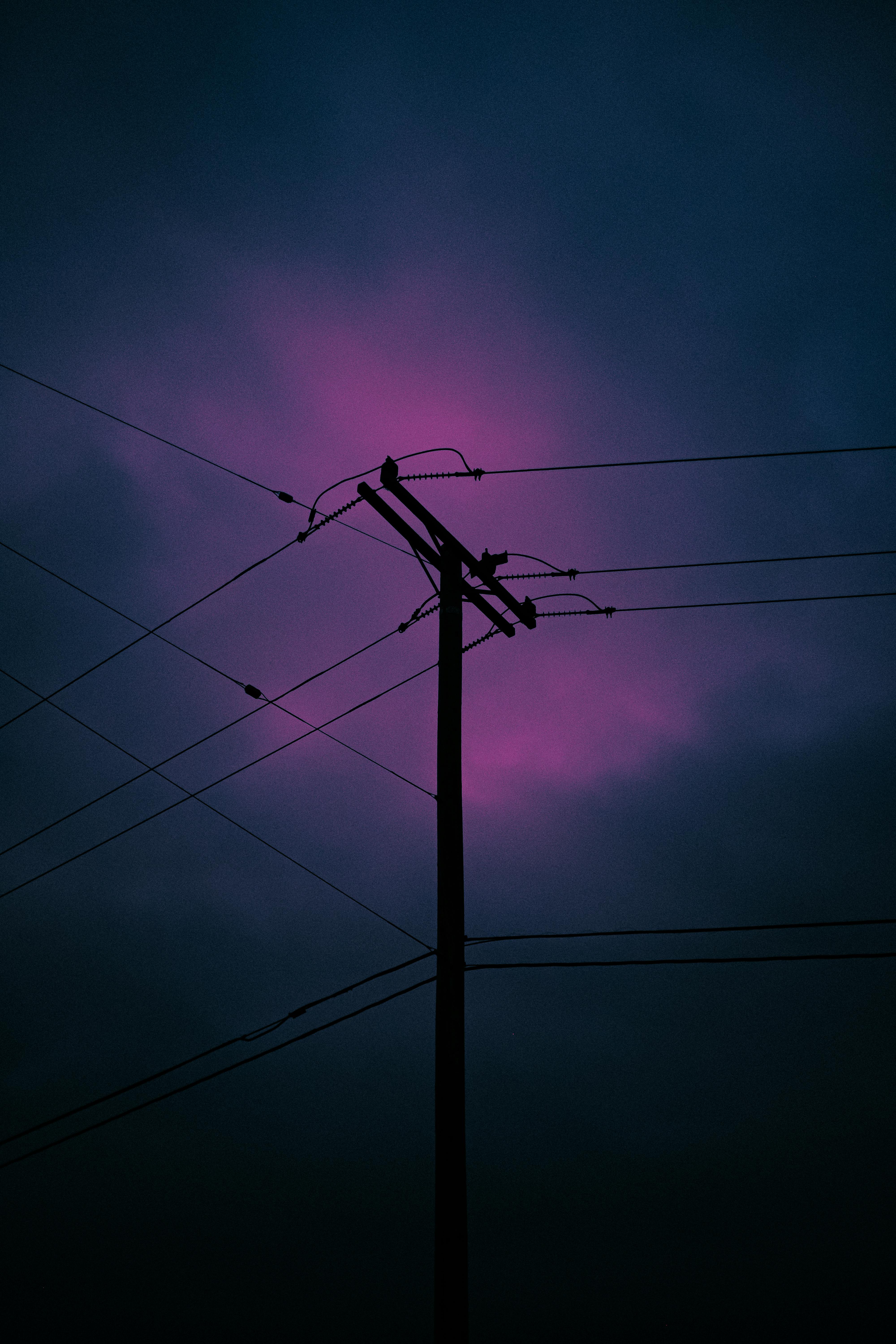A striking silhouette of a utility pole against a vivid purple dusk sky, capturing dramatic lighting and atmospheric mood.