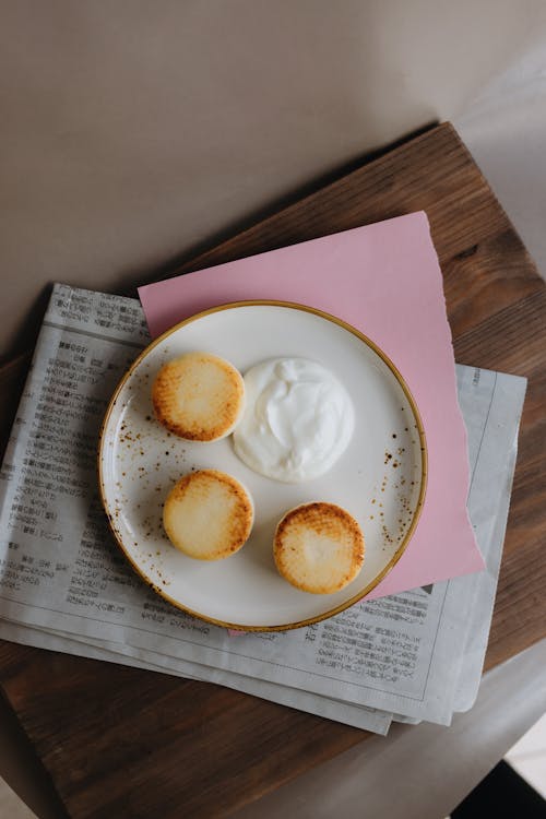 A plate with two cakes and a bowl of whipped cream