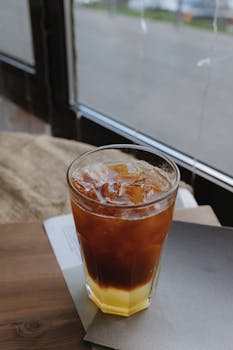 A close-up of a layered iced drink with brown liquid and ice cubes in a glass, perfect for a refreshment.