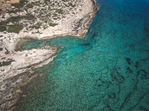 Free Stunning aerial view of a rocky coastline with clear turquoise waters along the shore. Stock Photo