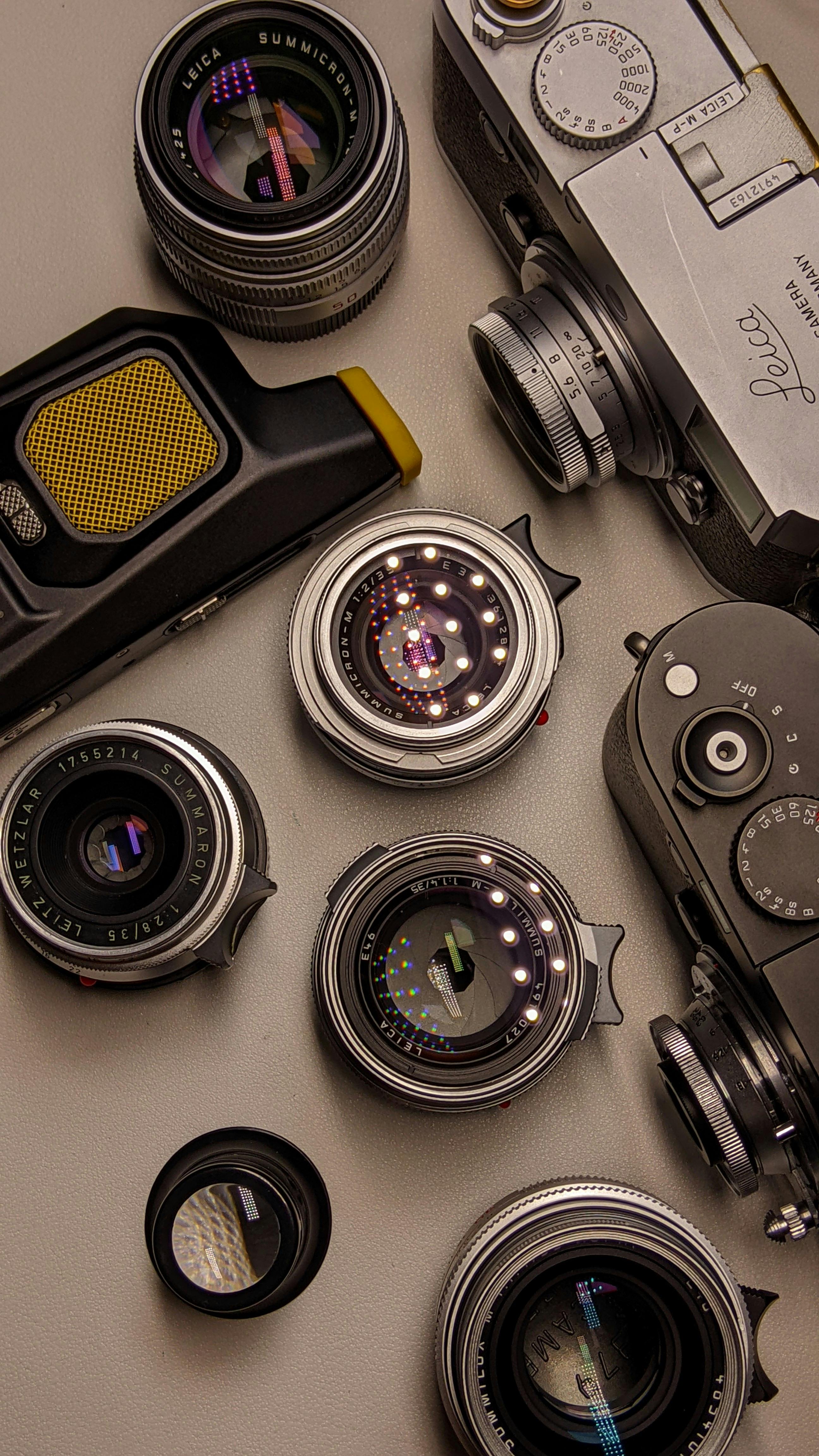 A flat lay of vintage cameras and lenses on a neutral background, emphasizing photography gear.