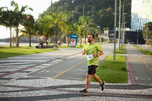 Free Man running a marathon on a scenic coastal road lined with palm trees. Stock Photo