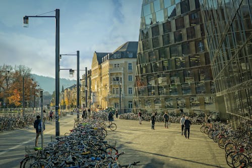 Grupo De Personas Caminando En La Calle Cerca De Bicicletas Y Edificio De Gran Altura