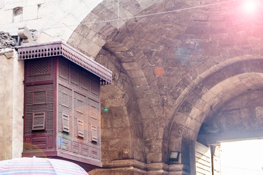 A detailed view of a historical stone archway featuring intricate wooden carvings and brickwork in warm daylight.