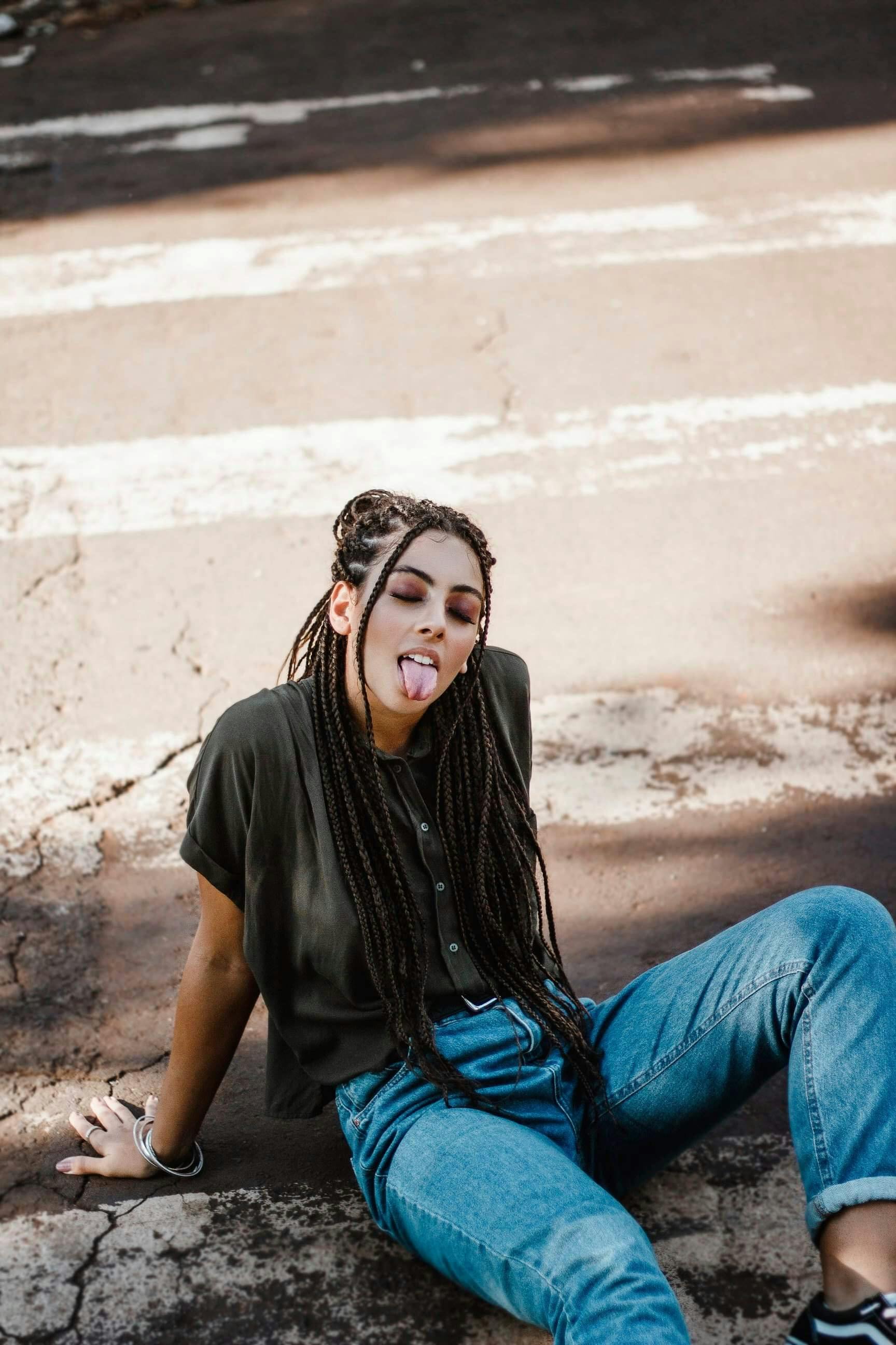 一位梳着辫子的时尚女性坐在阳光明媚的城市街道上