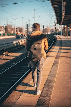 一个背着背包的男人，在城市日光下沿着火车月台行走，捕捉着旅程的瞬间