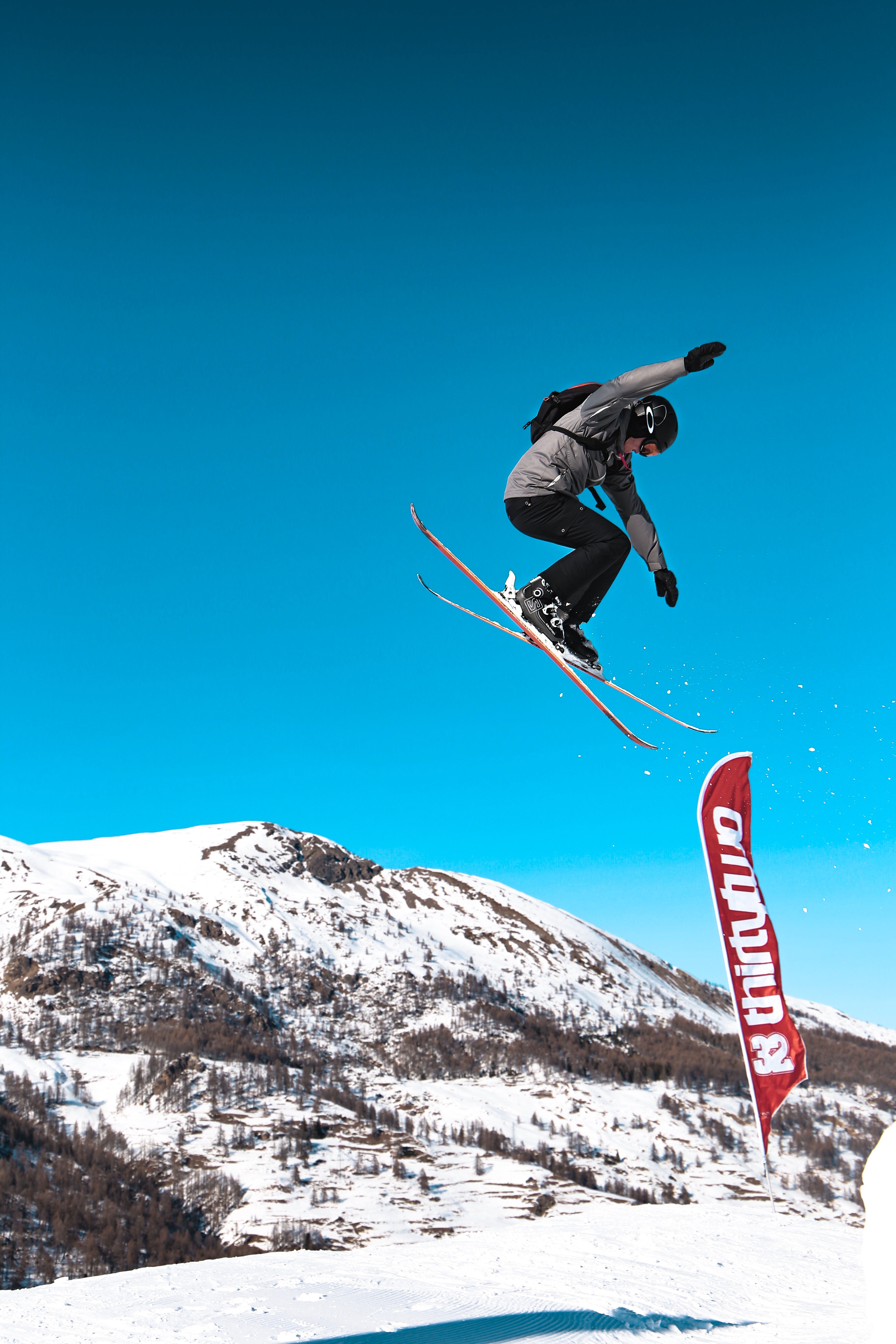 High-energy capture of a skier mid-jump against a stunning mountain backdrop.