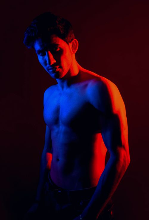 Free Artistic studio portrait of a topless man under blue and red lighting, conveying a dramatic and moody atmosphere. Stock Photo