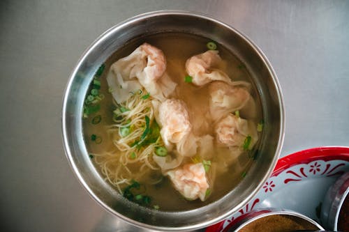 A bowl of soup with shrimp and noodles