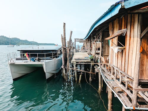 A boat docked at a wooden pier with a house