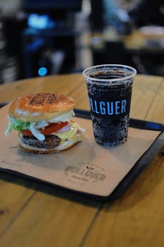 Delicious burger with fresh toppings paired with a soda on a tray, perfect for a satisfying meal.