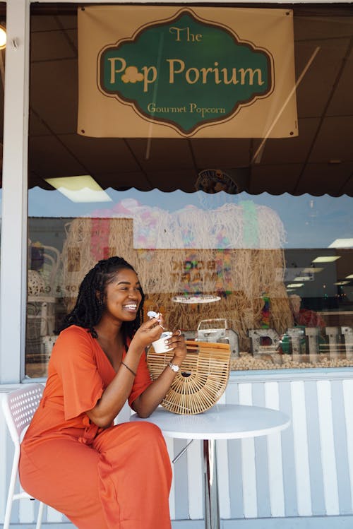 женщина улыбается и ест за пределами магазина поп пориум