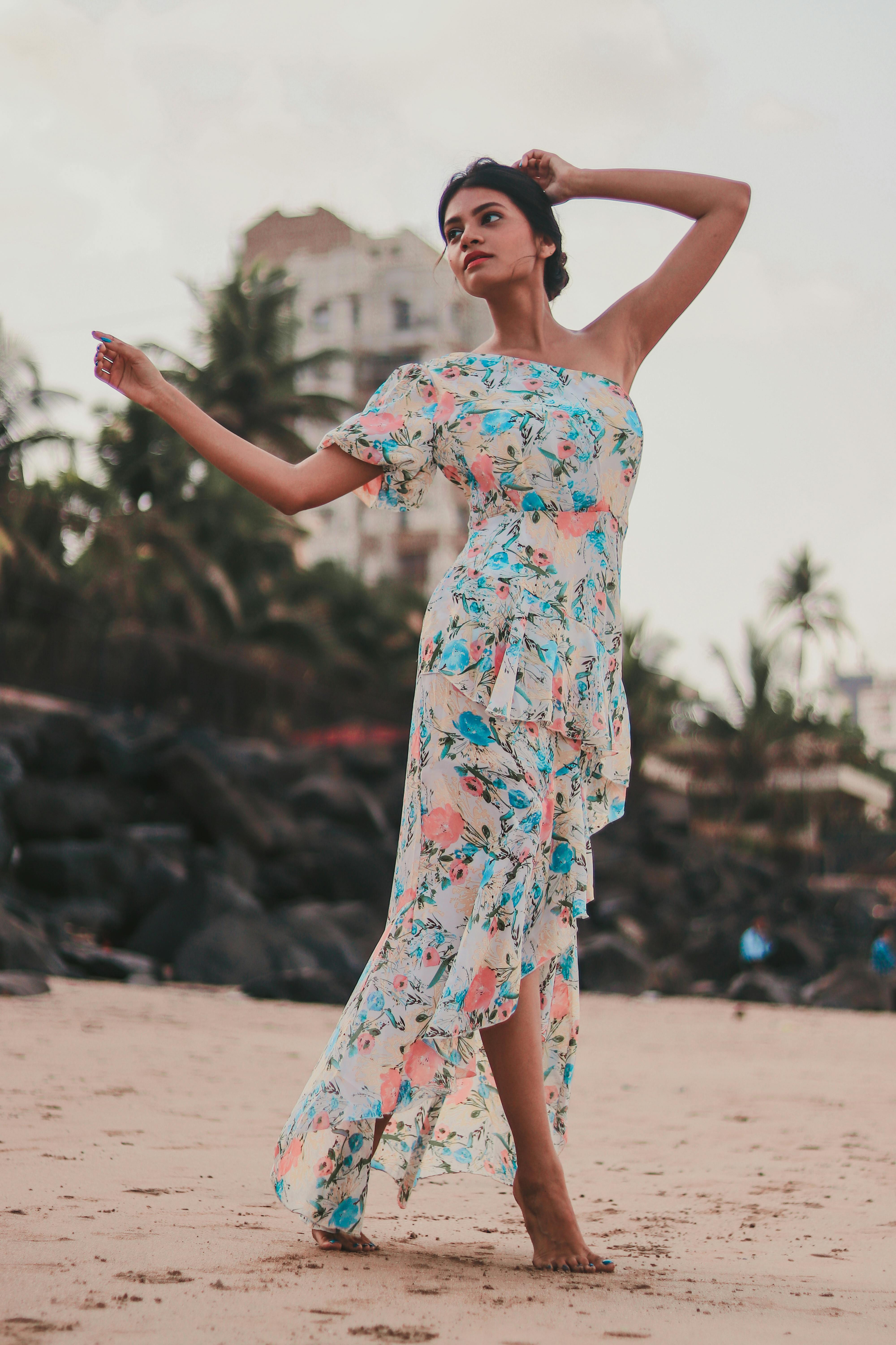 一位时尚女性身着花卉连衣裙，在孟买的海滩上优雅摆姿，捕捉着时尚与休闲的精髓