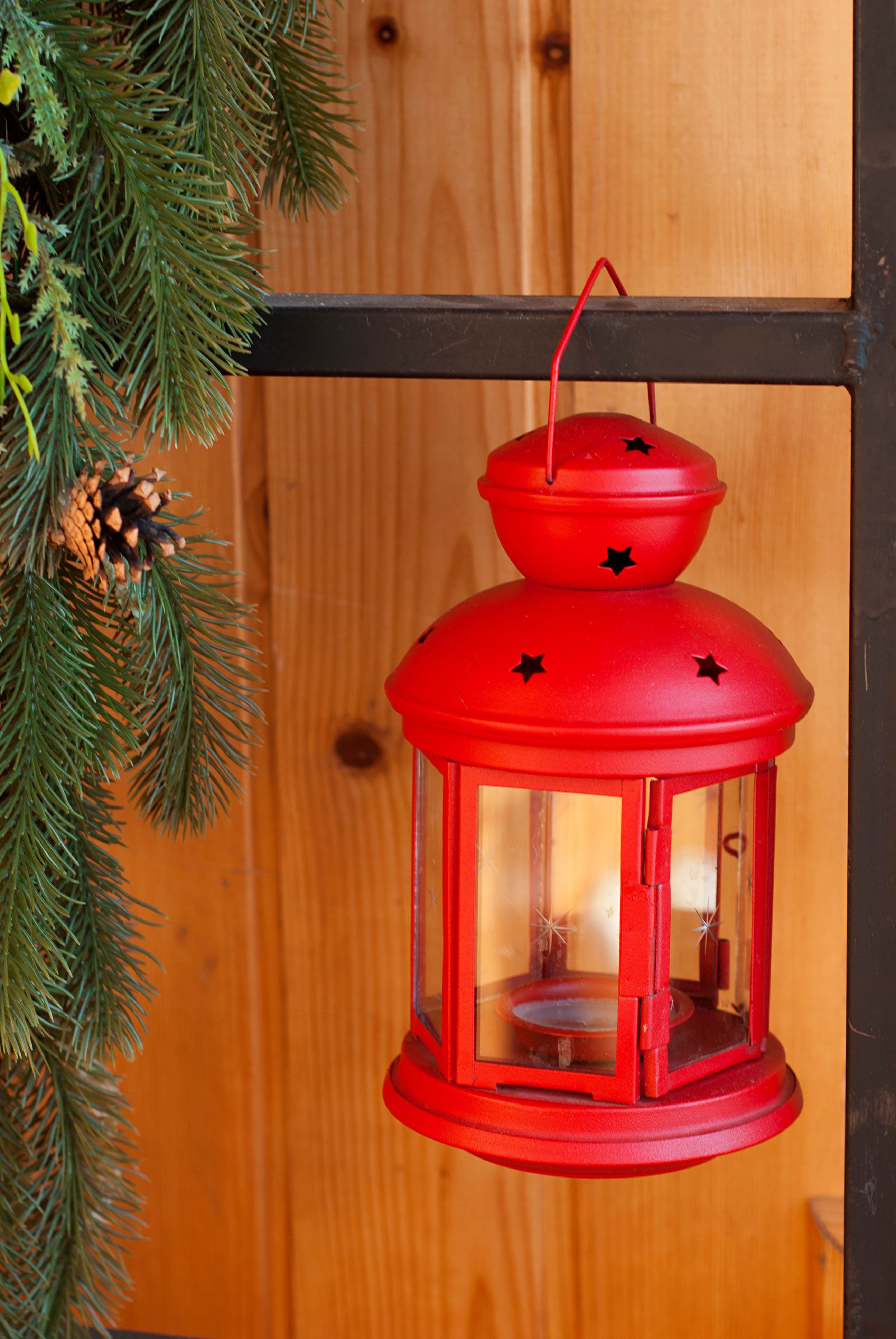 A vibrant red lantern hanging beside pine branches, perfect for holiday decor.