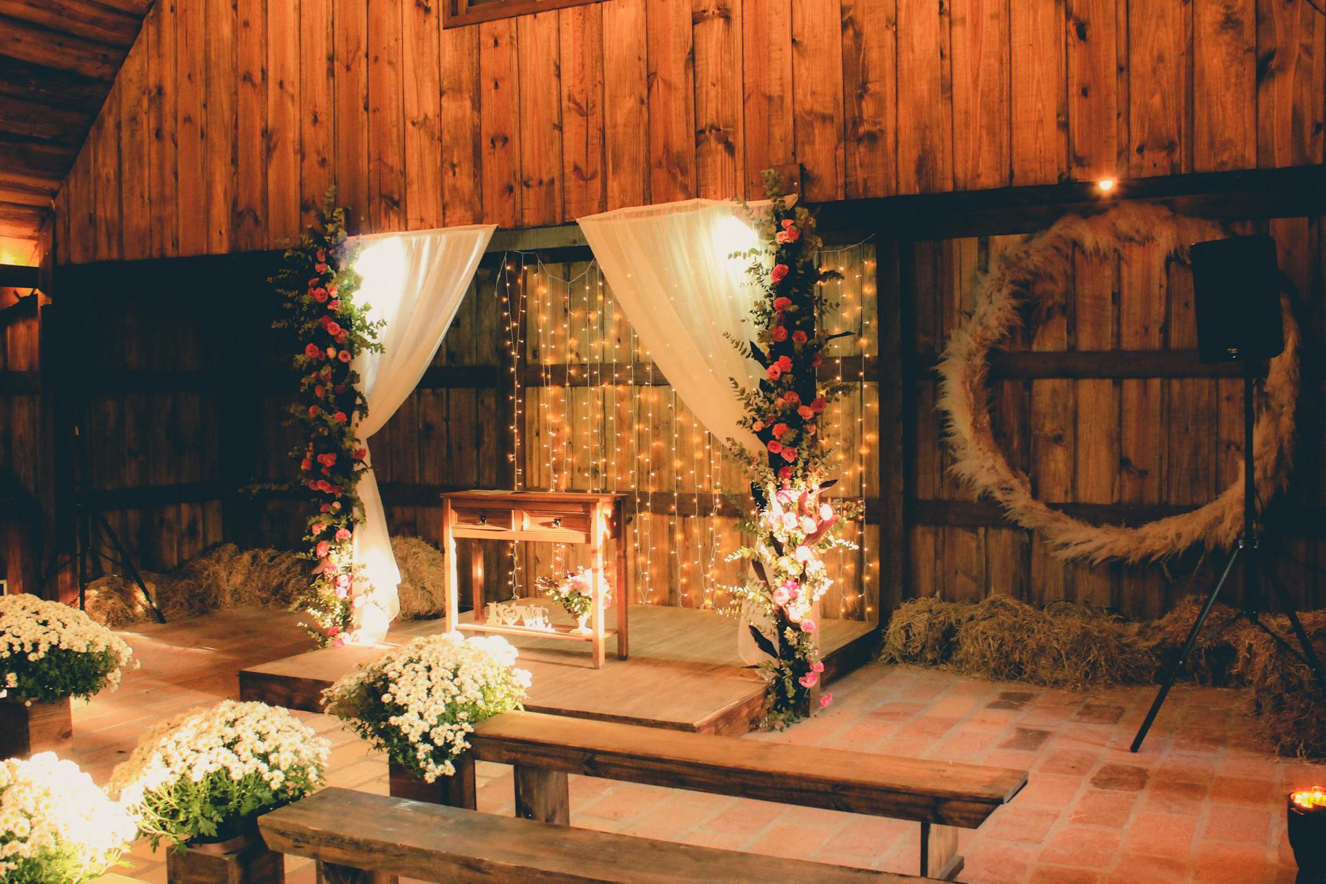 Charming rustic barn wedding setup with floral altar and warm lighting.