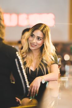 A young woman with blonde hair enjoys a lively evening at a stylish bar.