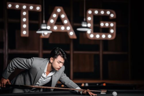 Free A focused young man in a gray suit playing pool in a stylish nightclub setting. Stock Photo