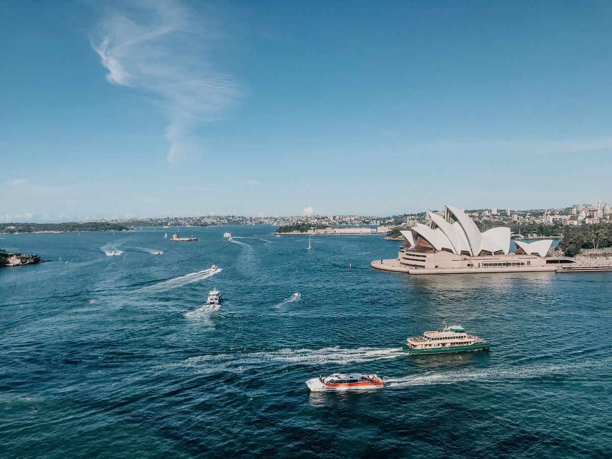 Sydney Opera House under a bright sky with sails reflecting in the water