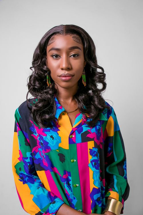 Free Close-up portrait of a young woman wearing a colorful shirt, showcasing modern African fashion. Stock Photo