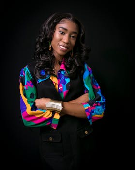 Stylish young woman in vibrant clothing poses confidently indoors against a dark background.
