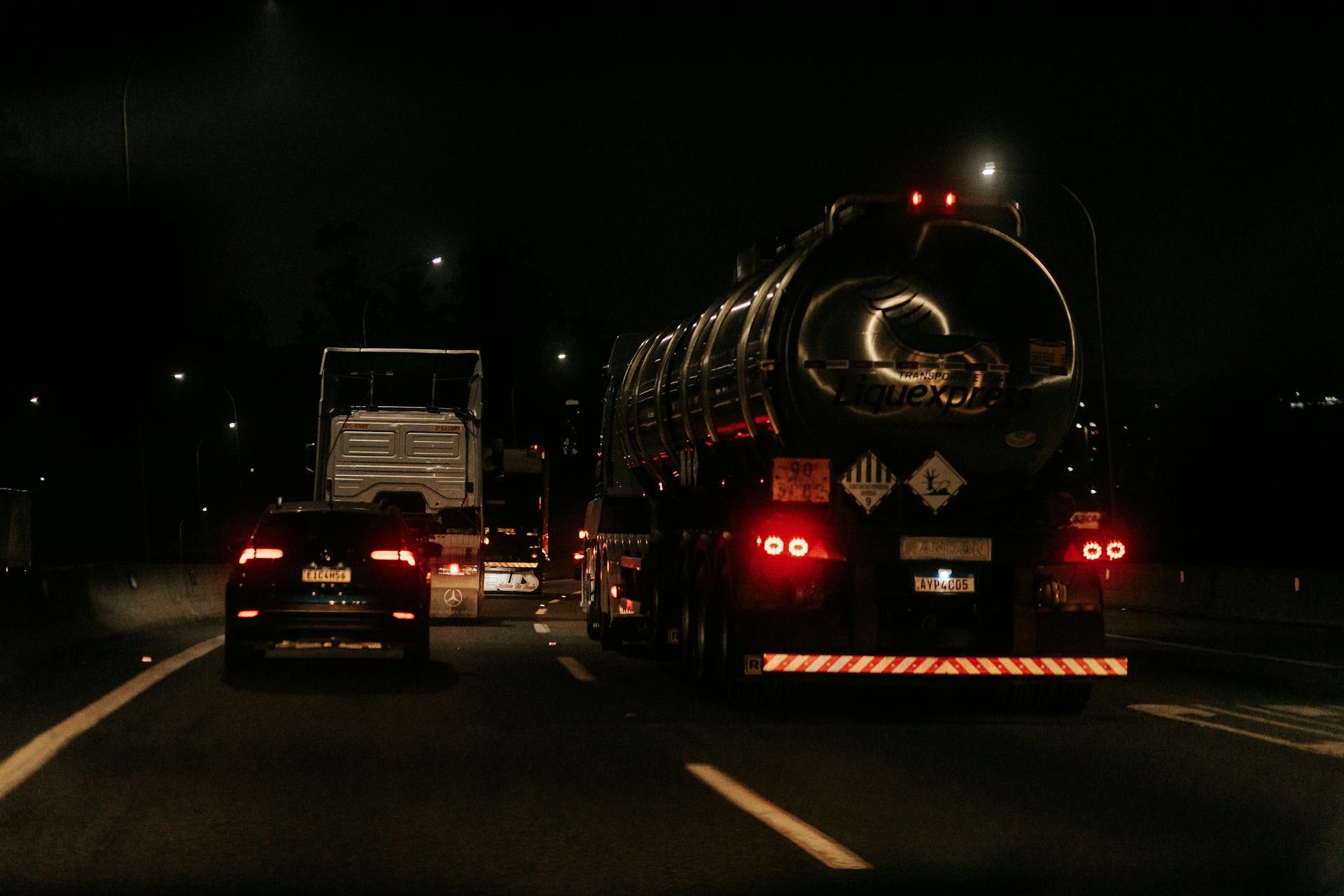 Vehicles drive down a dark highway at night, showcasing traffic and car lights.