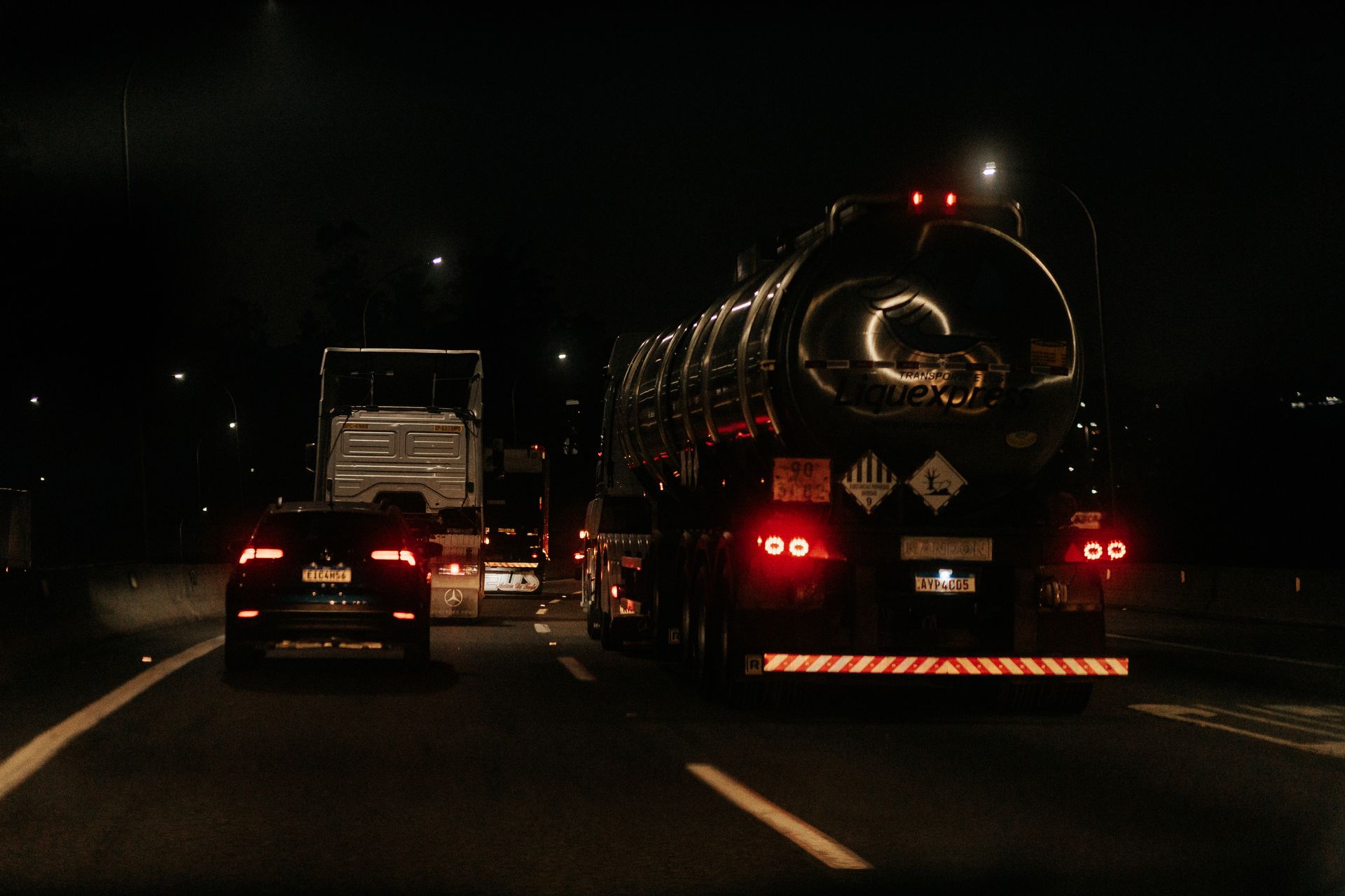 Vehicles drive down a dark highway at night, showcasing traffic and car lights.
