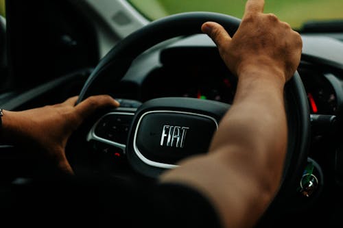 A person driving a car with their hands on the steering wheel