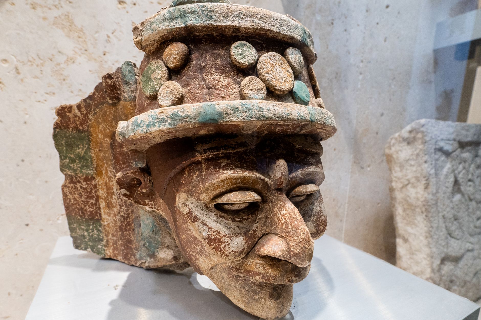 Close-up of an ancient Mayan sculpture head on display in Merida, Yucatan, Mexico, showcasing intricate stonework.