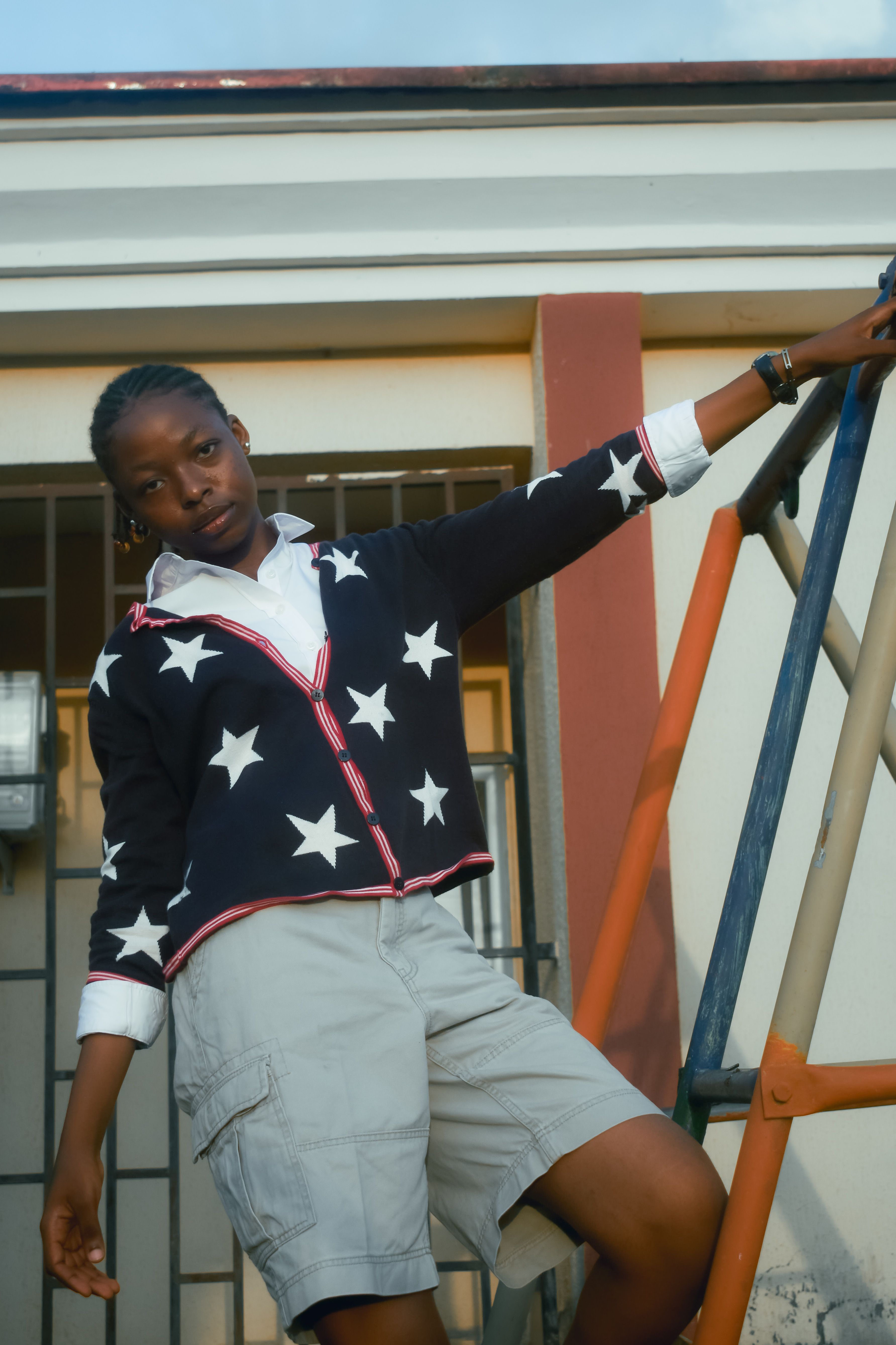 Stylish woman in a star-patterned cardigan poses outdoors, embodying modern fashion and casual elegance.