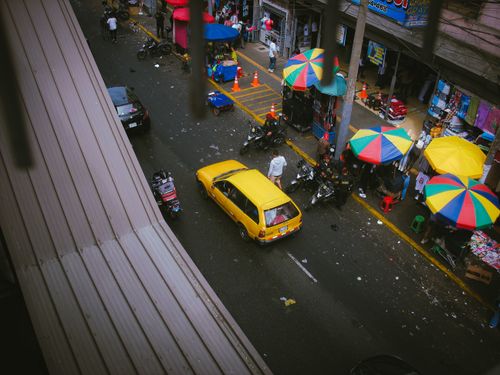Free An overhead view of a vibrant street market in Callao, Peru, with colorful umbrellas and traffic. Stock Photo