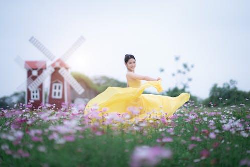 Free Smiling Woman in a Yellow Dress Dancing on a Meadow  Stock Photo