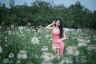 A woman in a pink dress is standing in a field of flowers