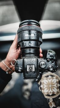 Close-up of a wet camera being held, capturing the essence of photography in rain.