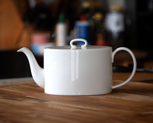 A white teapot on a wooden table