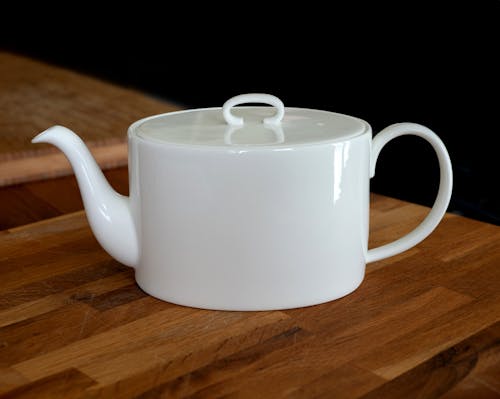 A white teapot on a wooden table
