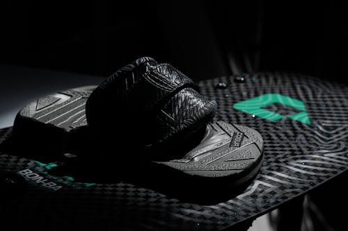 A pair of black and green flip flops on a black surface