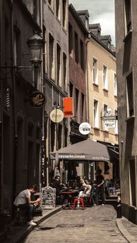Narrow European street with cozy outdoor cafés, vibrant urban settings, and people enjoying dining.