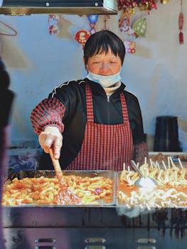 Asian woman cooking street food, wearing a mask in Shanghai market.