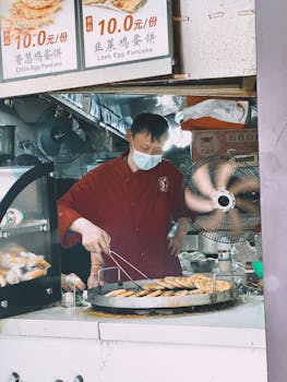 Street food vendor in Shanghai preparing chive and leek pancakes at an outdoor stall.
