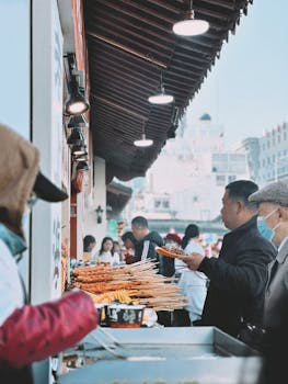 A bustling street food scene in Shanghai, China, featuring various skewers and vibrant activity.