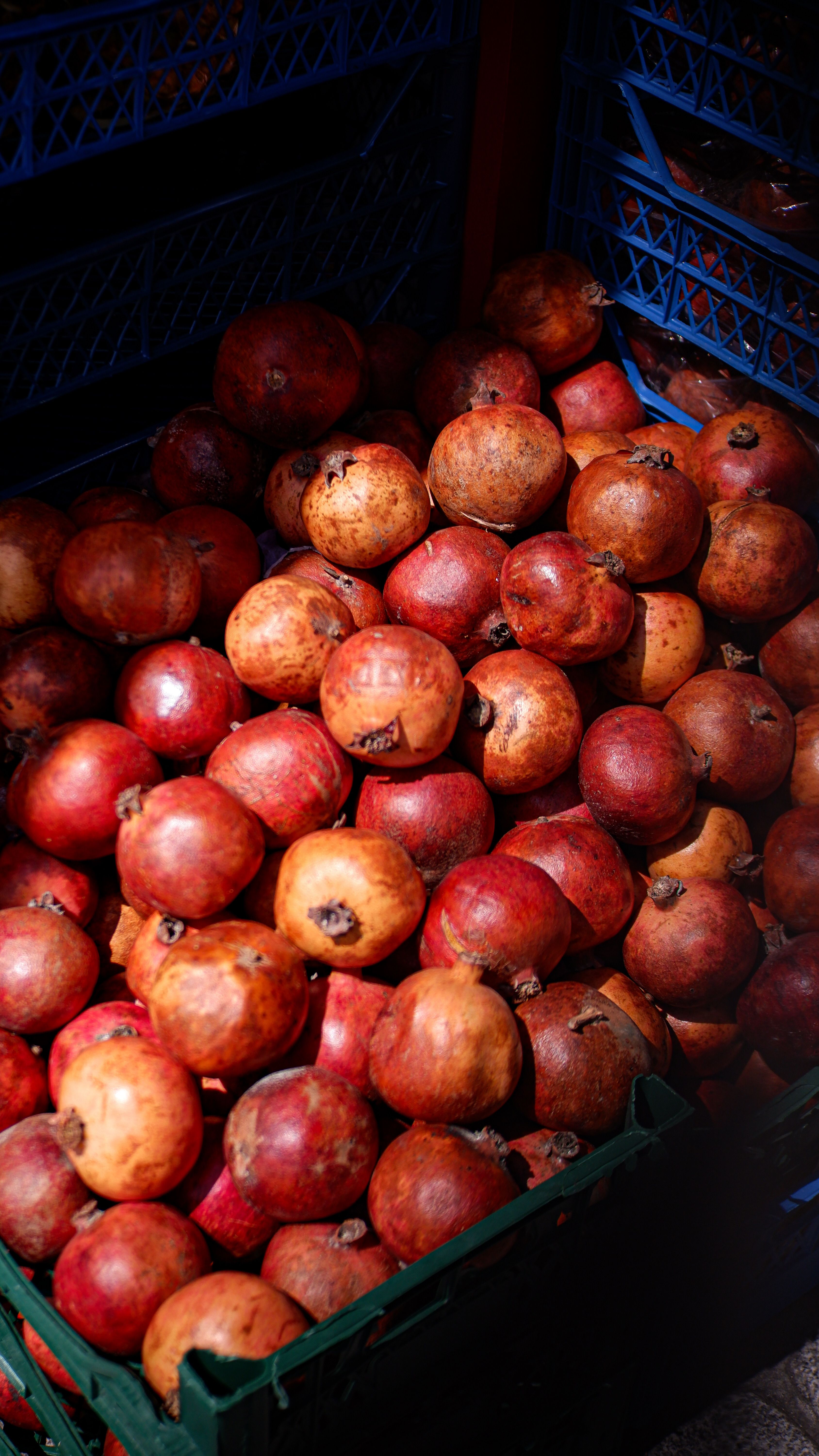 A vibrant display of fresh pomegranates in a market crate, capturing their natural color and texture.