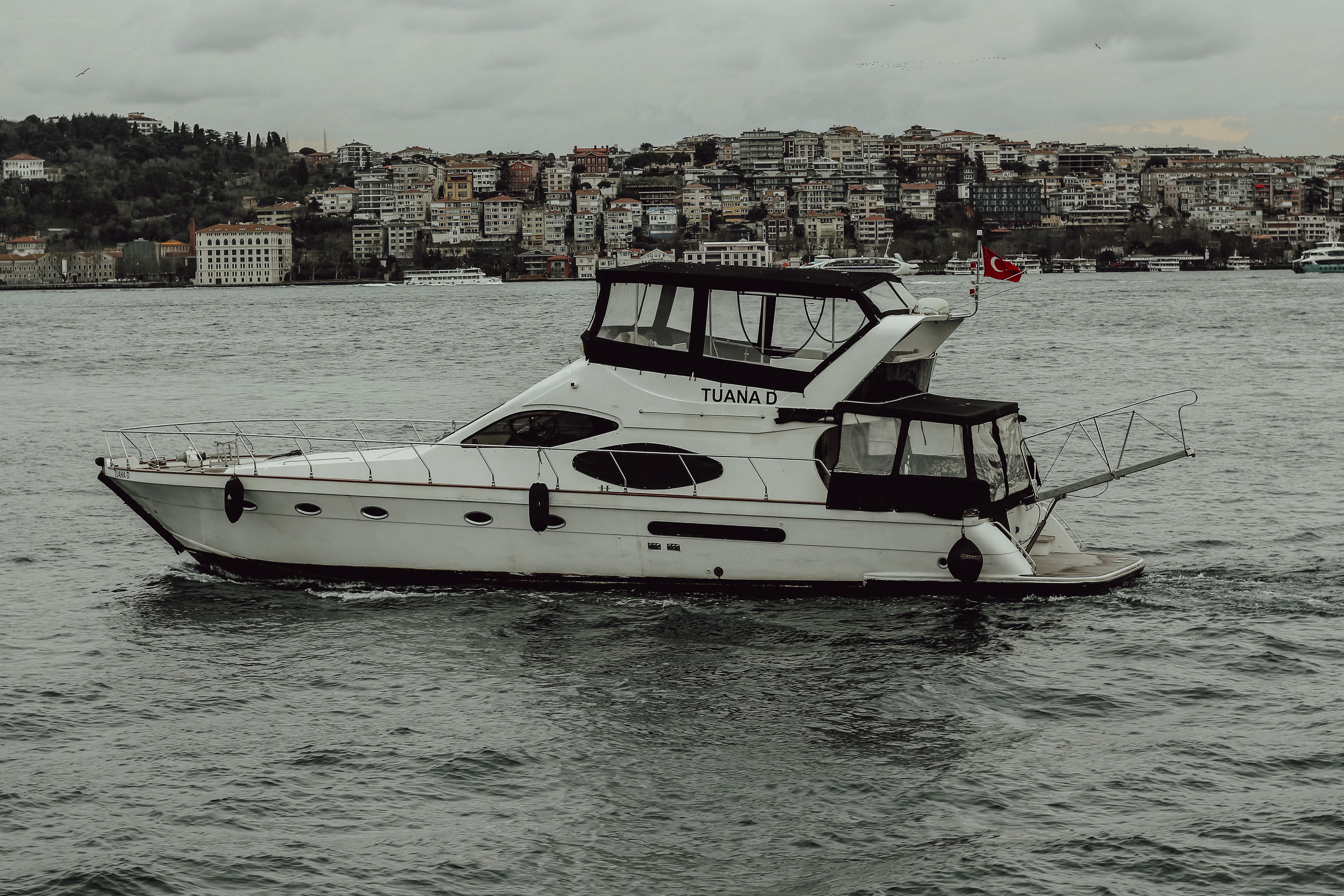 Elegant motor yacht sailing through the Bosphorus Strait with Istanbul cityscape in the background.