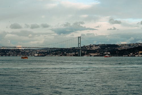 A boat is sailing across the water with a bridge in the background