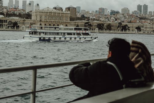 A man and woman sitting on a boat looking at a city