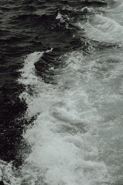 A black and white photo of waves on a boat