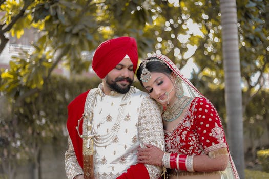 A joyful Sikh couple in traditional wedding attire embracing outdoors.