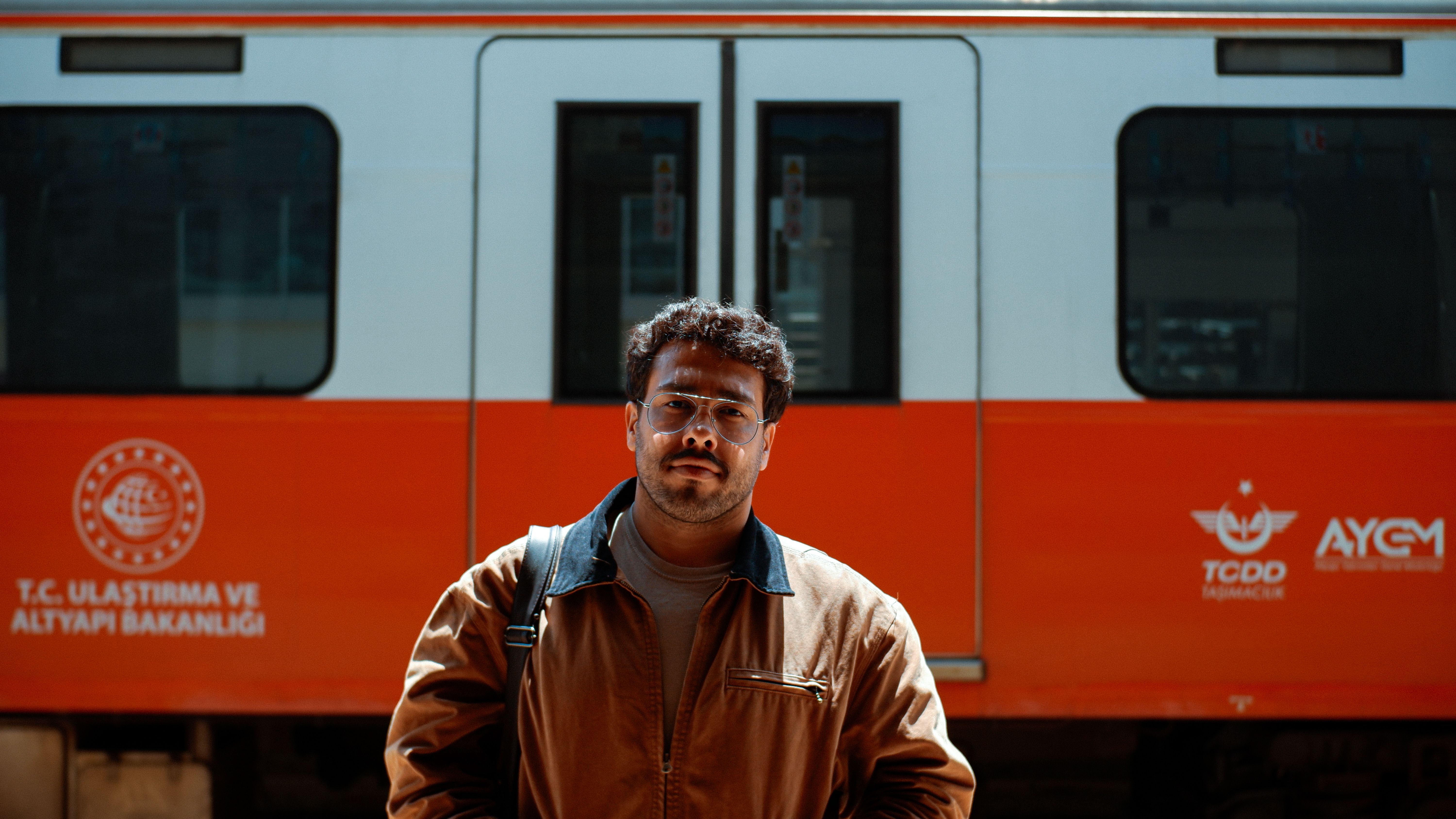 Man with Eyeglasses and Brown Jacket on the Platform of the Railway Station